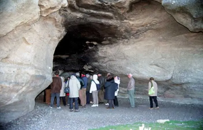 Grupo de visitantes dentro de una cueva de roca cerca de El Calafate