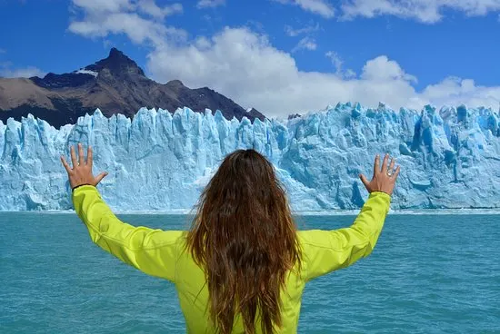 Persona de espaldas con los brazos en alto frente al Glaciar Perito Moreno, en la navegación corta