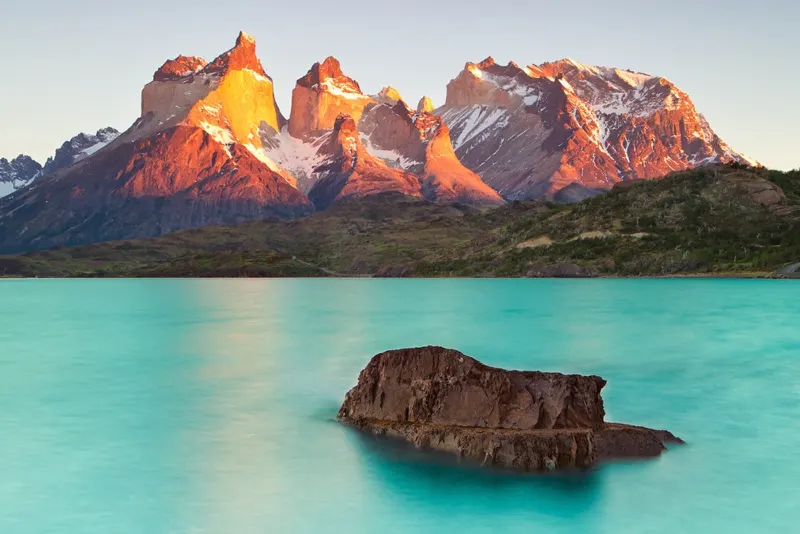 Cuernos del Paine con luz anaranjada sobre un lago de aguas turquesa